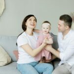 Smiling family with a toddler enjoying quality time on the couch at home.